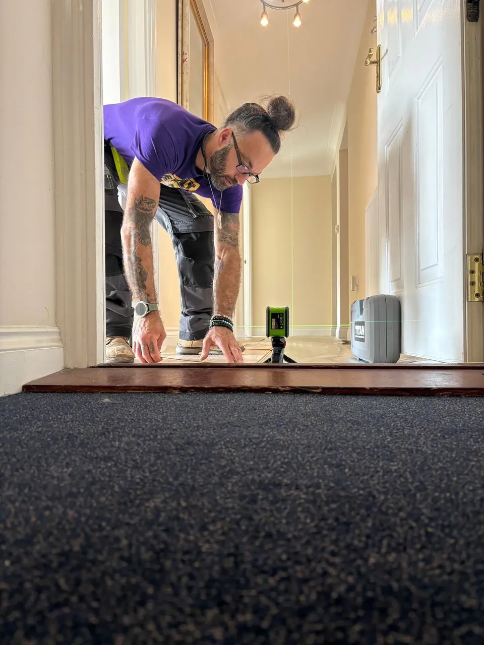 Ryan from Pav's Flooring setting out a floor with a green laser level